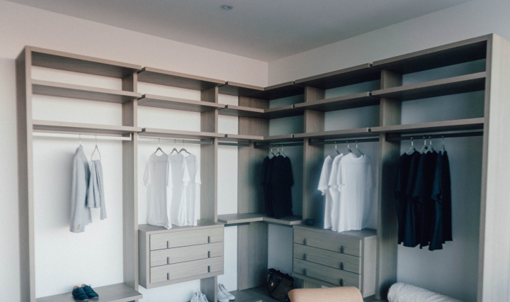 An image of an open closet unit with monochrome clothing on hangers.